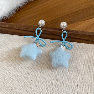 Detail showing the light blue flocked star pendant and metal bow on the pearl earrings