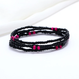 Macro detail of double-layer black and rose red beaded waist chain on white fabric