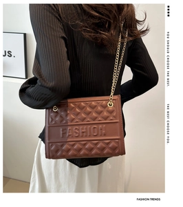 Detail of brown quilted shoulder bag with gold chain strap and FASHION embossed texture