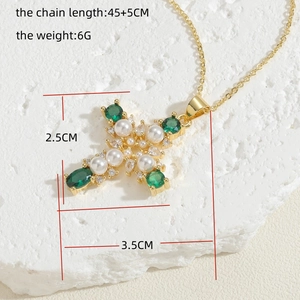 Close-up of 14K gold cross necklace featuring green zircon, pearls, and size dimensions