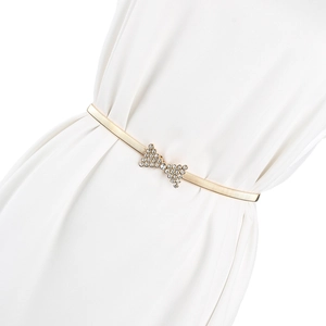 Détail d'une ceinture élastique dorée avec boucle nœud en strass sur robe