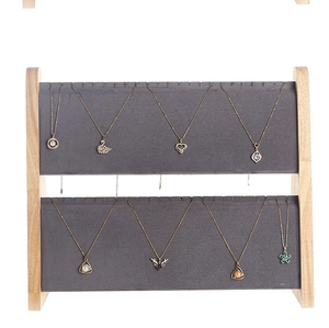 Detail of two-tier wooden necklace display stand with gray velvet slots for jewelry storage