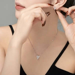 Detail of S925 sterling silver heart necklace and earrings set worn by a model