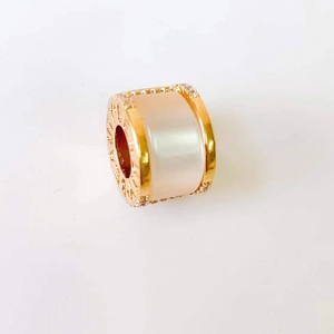 Macro shot of 18k gold rose clover cylinder pendant with white inlay and carved details