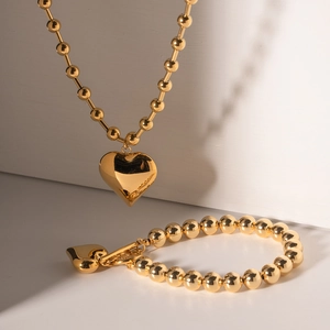 Golden stainless steel beaded jewelry set featuring a 3D heart pendant necklace and bracelet