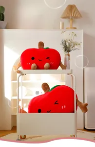 Detail of cute red apple plush pillows with smiling faces in a cozy home setting