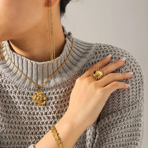 Close-up of elegant gold flower necklace and tassel earrings on female model