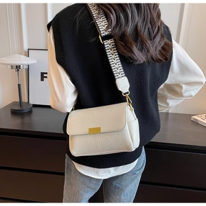 Détail du sac blanc en cuir litchi avec large bandoulière ondulée et boucle dorée