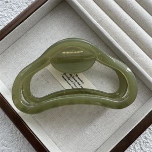 Detail of a green translucent resin hair claw clip with a hollow ring design and gold spring