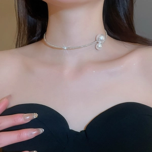 Detail of silver rhinestone choker necklace with white pearl accents on model neck
