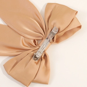 Macro shot of the champagne satin bow hair clip back with a silver metal spring clasp