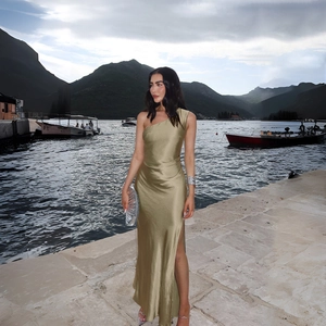 Detail of elegant olive gold satin dress featuring one-shoulder design and high side slit