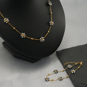 Bohemian gold necklace and bracelet set with crystal flower charms on display