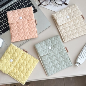 Quilted heart pattern pouches in pastel colors with snap button closure on desk