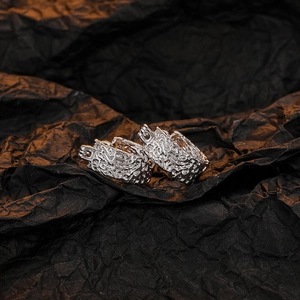 Macro shot of silver lava texture earrings on a textured black paper backdrop