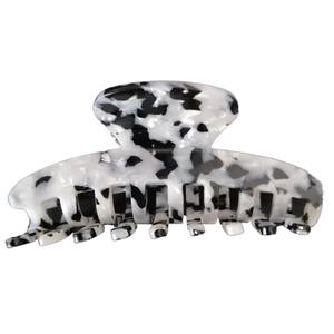 Close-up of a large acetate hair claw clip featuring a classic black and white cow print