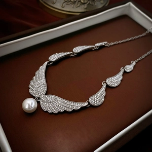Macro shot of silver angel wing necklace with sparkling rhinestones and a large white pearl