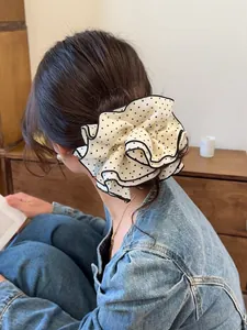 Close-up of a large black and white polka dot scrunchie styled on a classic hair bun