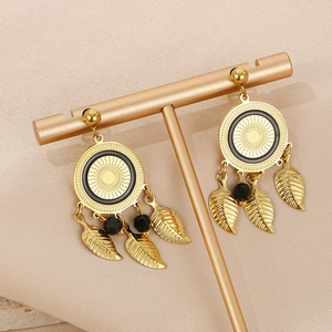 Gros plan de boucles d'oreilles plume dorées style bohème avec perles sur présentoir