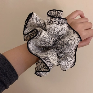 Gros plan d'un chouchou double épaisseur avec dentelle blanche et motif floral noir