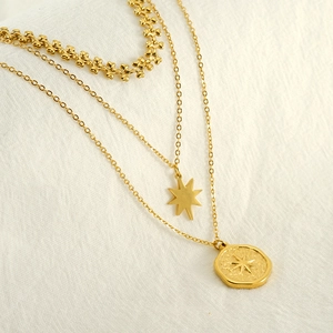 Detailed close-up of triple-layered gold stainless steel necklace with star and coin pendants