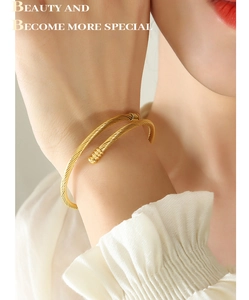 Close-up of a minimalist golden spiral open bangle on a wrist with elegant polished finish