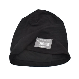 Detail of black ribbed knit beanie featuring a grey woven logo patch with white text