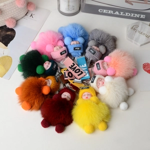 Top view of colorful plush sleeping baby keychains with fox fur pom poms and knit caps