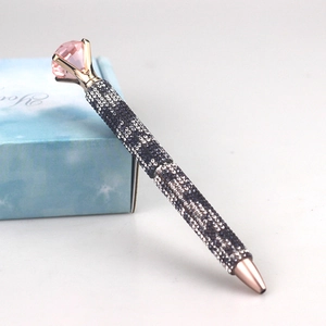 Close-up of luxury rose gold ballpoint pen with pink crystal and blue rhinestones