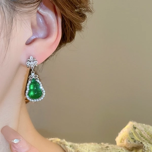 Dettaglio ravvicinato degli orecchini a zucca verde smeraldo con zirconi su una modella