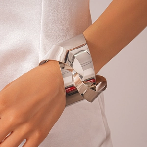 Detail of a large silver metallic knotted cuff bracelet with a polished mirror finish