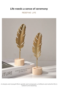 Close-up of dual gold metal feather sculptures on natural round wooden bases