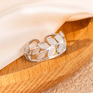 Minimalist silver stainless steel open ring with intricate hollow leaf design on wooden base