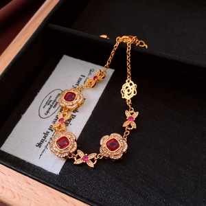 Detail of 24K gold-plated flower bracelet with ruby-red stones in a black velvet box