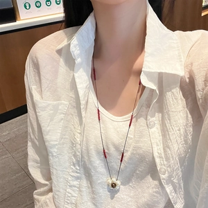Detail of flower pearl pendant with red beads on black long necklace for women