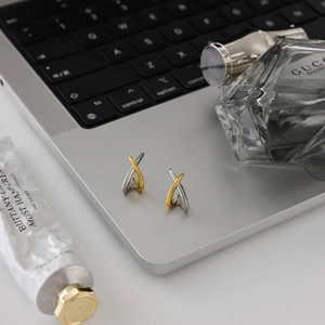 Macro view of minimalist mixed silver and gold tone stainless steel earrings