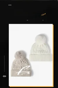 Close-up of thick jacquard knit hats in beige and khaki with large faux fur pom-poms