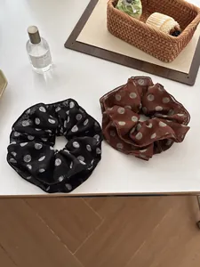 Detail of two chiffon scrunchies with polka dot patterns in black and brown colors