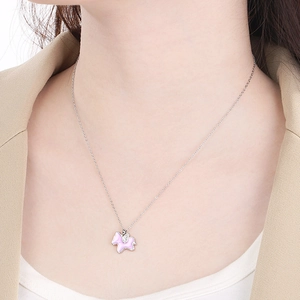 Detailed close-up of a silver unicorn necklace with a pink cloud pendant on a model's neck