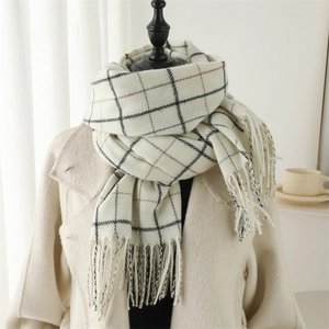 Close-up of soft plaid scarf with tassels on neutral background with warm coffee cup