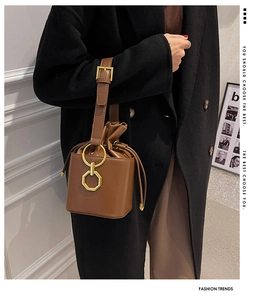 Detail of vintage brown leather bucket bag with gold hardware and drawstring closure