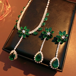 Macro shot of glittering flower and teardrop jewelry set with green gems and diamonds