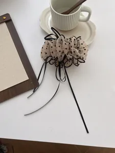 Polka dot organza scrunchie with long black ribbons on a minimalist desktop setup