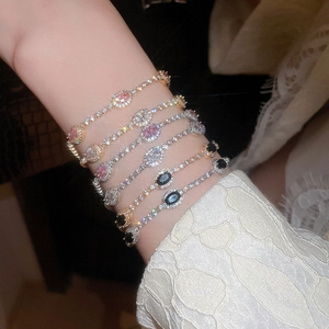 Close-up of stacked zirconia adjustable bracelets in gold and silver finish with colored stones