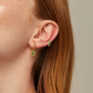 Detail of gold-plated earrings set with emerald green zircon stones on female model