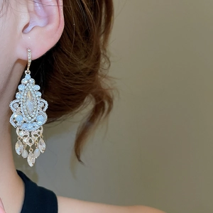 Macro side view of a model wearing a gold waterdrop tassel crystal earring in Baroque style