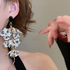 Close-up of leopard print fabric flower drop earrings with gold fringe on model