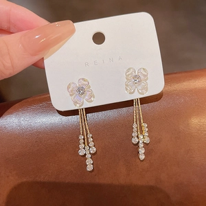 Detailed macro view of a gold floral earring with rhinestone tassels on a brown texture