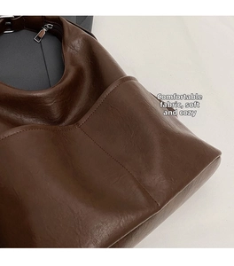 Detailed view of deep brown tote bag featuring soft pleated PU leather texture and silver zipper