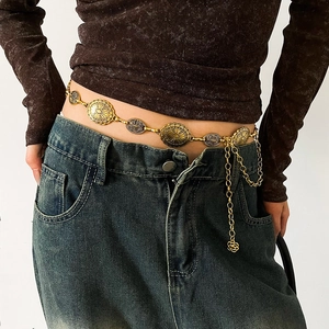 Detailed close-up of retro gold metal waist chain with geometric relief on denim jeans